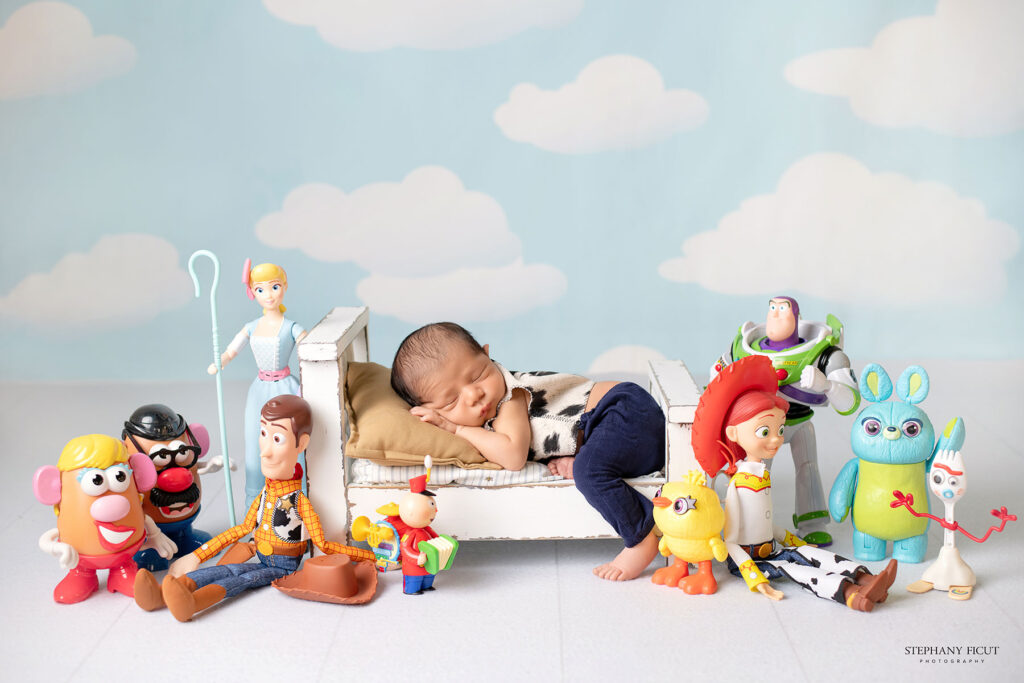 Newborn posed inside a Toy Story-inspired prop with soft cowboy and space-themed toys. Dallas-Fort Worth newborn photographer Stephay Ficut captures creative setups for families.